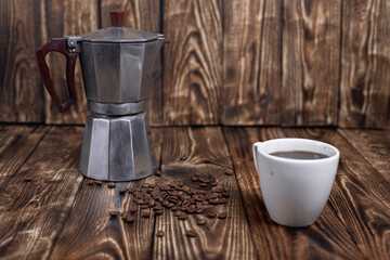 Steamed Moka pot with coffee beans on a dark wood table vintage photo