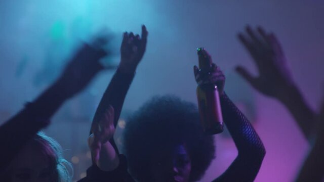  Slowmo tracking of young people dancing with raised arms at party