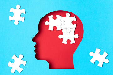 Papercut head with jigsaw puzzle pieces inside. Mental health problems, psychology, memory, logic,...