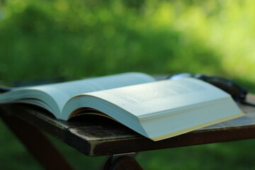 Bücher und Sonnenbrillen stehen auf dem Kaffeetisch, Gras und Fluss sind dahinter sichtbar