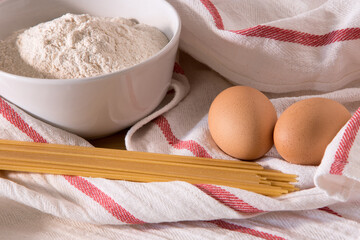Gourmet close up with a bowl full of flour, spaghetti and two eggs