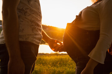 Silhouette of a guy and a pregnant girl on a sunset background in warm colors