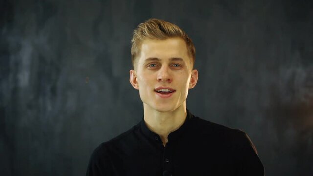 Smiling young man look at camera and recording vlog in loft studio