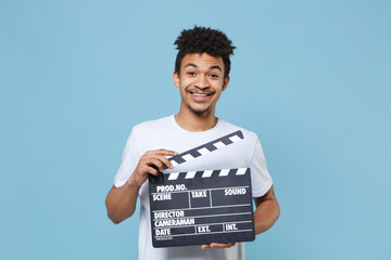 Funny young african american guy in casual white t-shirt posing isolated on blue background studio...