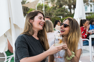 Two friends drinking beer, toasting and laughing in a bar