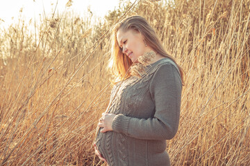 Happy pregnant woman enjoys life and relaxes in nature.