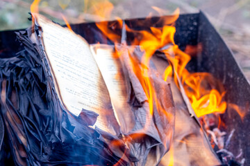 Fire engulfs the pages of an open book. Burning a book