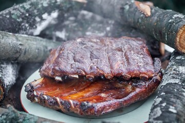 Sliced fresh hot pork ribs lie outside on a plate at a picnic