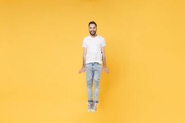 Fototapeta na wymiar Cheerful young bearded man guy in white casual t-shirt posing isolated on yellow wall background studio portrait. People sincere emotions lifestyle concept. Mock up copy space. Jumping having fun.