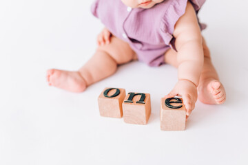 the baby's hands hold square letters. the word one is built from letters