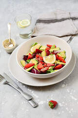 avocado salad with sesame and strawberries on a white plate. fitness keto food recipe. healthy lunch