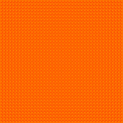 orange base template of plastic construction brick. Plastic toy blocks background in orange. Construction plate base for children's toys. Repeating texture and empty field for bricks installation