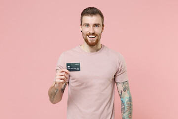 Cheerful young bearded tattooed man guy in pastel casual t-shirt posing isolated on pink wall...