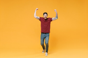 Fototapeta na wymiar Screaming young bearded tattooed man guy in casual t-shirt black cap posing isolated on yellow background. People emotions lifestyle concept. Mock up copy space. Expressive gesticulating with hands.