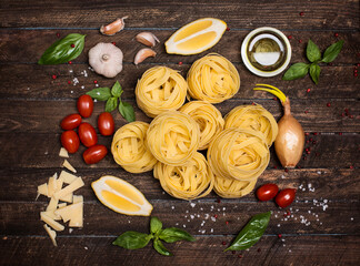 Fettuccine with ingredients for cooking pasta on wooden background, top view.
