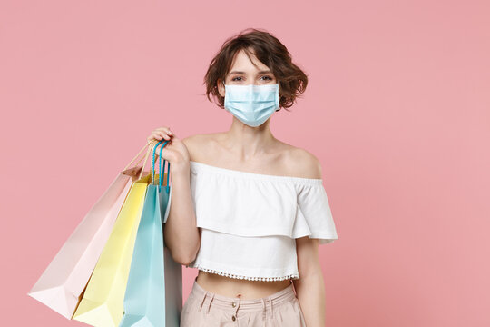 Pretty young woman girl in summer clothes sterile face mask hold package bag with purchases isolated on pastel pink wall background studio portrait. Shopping discount sale concept. Mock up copy space.