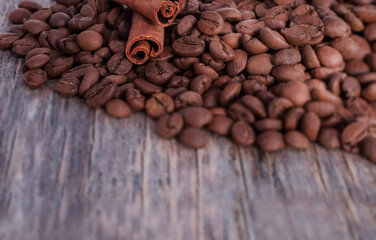 coffee beans with two cinnamon sticks on a wooden gray and pink surface