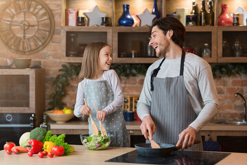 Happy father and daughter having fun while cooking lunch together in kitchen