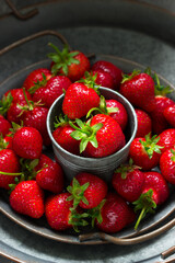 Ripe red strawberries with stems on an iron tray, berry pattern.