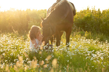 Frau kuschelt mit Pferd in Blumenwiese