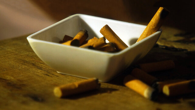 Cenicero con colillas de cigarrillo, vicio de fumar.