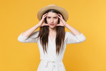 Sick tired young brunette woman girl in white dress hat posing isolated on yellow background studio portrait. People emotions lifestyle concept. Mock up copy space. Put hands on head, having headache.