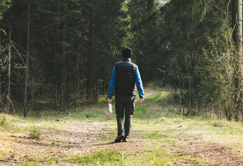 Man in a fleece takes off mask after quarantine, enjoys walking in forest alone. End of  coronavirus, lockdown and beginning of normal life. View from behind. Quarantine over concept