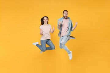 Fototapeta na wymiar Cheerful young couple two friends guy girl in pastel blue casual clothes posing isolated on yellow background studio portrait. People lifestyle concept. Mock up copy space. Jumping, showing thumb up.