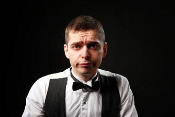 Portrait of a young and handsome man with emotion and funny face in black bow-tie isolated on black background.with copy space. 