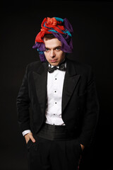 Funny magic man in tuxedo and bow tie with colorful handkerchief isolated on black background