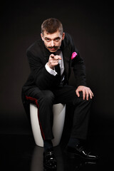 Portrait of a young and handsome man with emotion and funny face in black bow-tie isolated on black background.with copy space. 