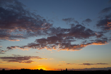 Fototapeta na wymiar Clouds on a background of blue sky. Beautiful orange sunset.