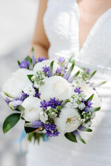 Brides wedding bouquet with peonies, freesia and other flowers in women's hands. Light and lilac spring color. Wedding day. Bouquet with love