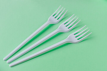 Three plastic forks on a green background.