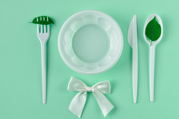 Plastic utensils on a green background with green leaves.