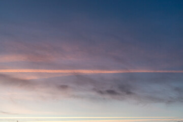 Fototapeta premium footprints of the plane in the sunset over the city in a cloudy sky