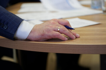 The hand of a male leader holds a fountain pen during an important meeting or filling out...
