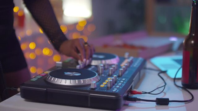  Slow motion mid-section of hands of unrecognizable female DJ using controller and mixing music at party