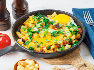 Fried eggs with potato in cast iron pan.