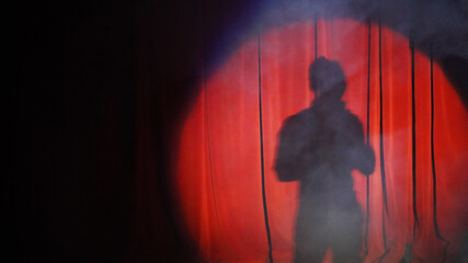 the shadow of a man in the light of spotlights on the red wings. stage, performance. round ray of light