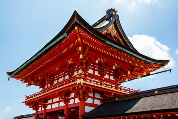 Bright, red religious pagoda with gold trim in Tokyo, Japan against a blue sky with puffy clouds.