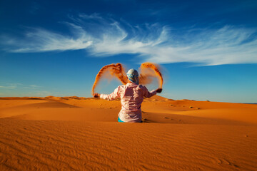 Single Man throws sand in the Sahara desert at sunset.