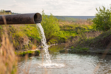 water flows from a pipe into a river against the backdrop of nature. The concept of nature...