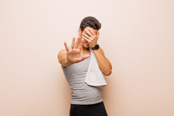 young arabian man covering face with hand and putting other hand up front to stop camera, refusing...