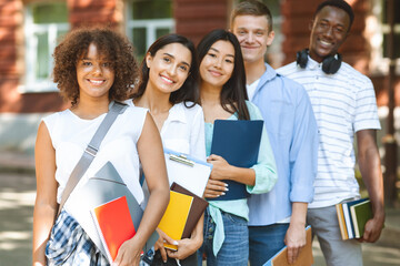 Group of international students posing near college building, smiling at camera
