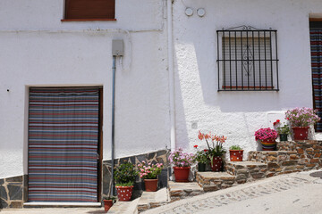 Trevelez village in the Alpujarras mountains, province of Granada, Andalusia, Spain - May 29, 2019: - narrow cobblestone street with whitewashed houses and flower pots.