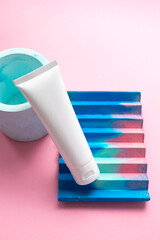White moisturizer cream tube on abstract concrete decor on cute pink background and copy space for text. Mockup hand moisturizer, shampoo or facial cleanser container