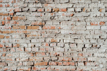 Old red brick wall with remnants of plaster and gray cement. Background