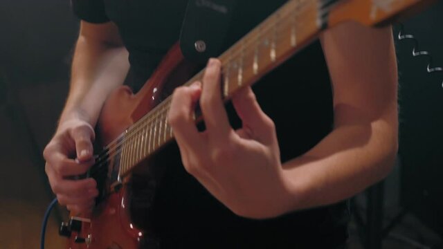 Close-up male hands of professional guitarist playing on electric guitar enjoying live session