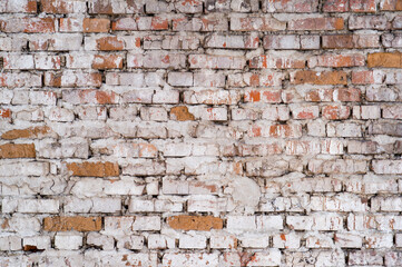 Old red brick wall with remnants of white plaster and grey cement. Background
